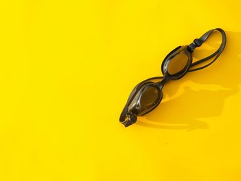 High angle view of eyeglasses on yellow background