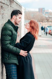 Side view of young couple standing in city