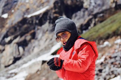 Boy in sunglasses and warm clothing holding snow outdoors