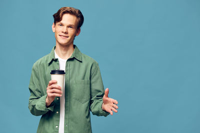Portrait of young man standing against blue background