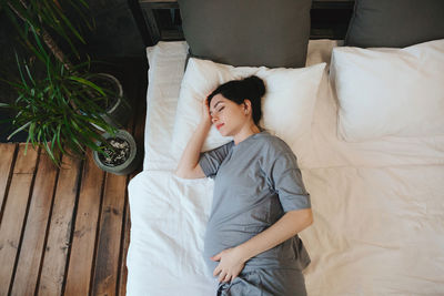 Portrait of young woman sitting on bed at home