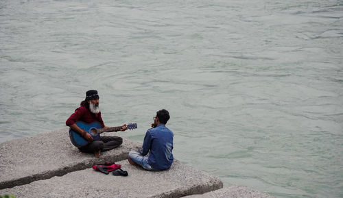 High angle view of friends sitting on shore