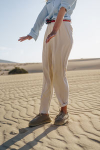Low section of woman standing on sand