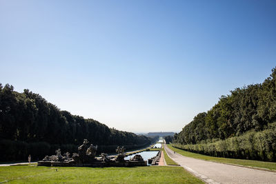 Road amidst trees against clear blue sky