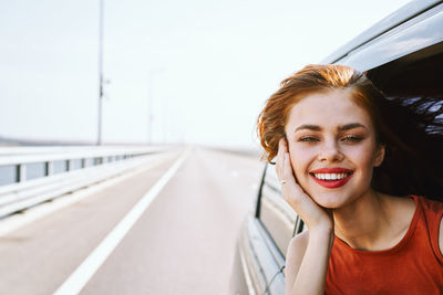 Portrait of young woman standing against sky