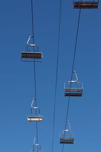 Low angle view of ski lift against clear blue sky