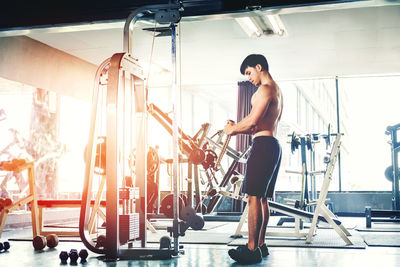 Shirtless young man exercising gym