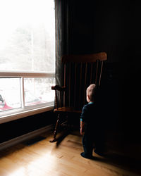 Rear view of upset baby looking out window