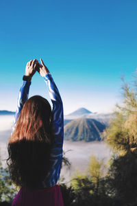 Rear view of woman standing against sky