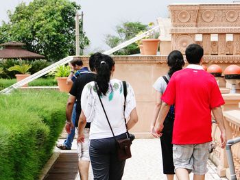 Rear view of people walking on staircase against building