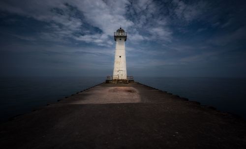 Lighthouse by sea against sky