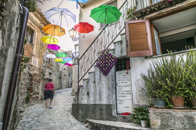 Rear view of woman walking on alley amidst buildings