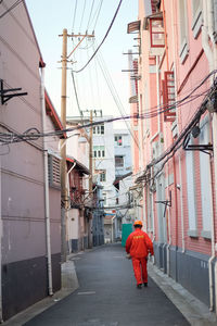 Rear view of man walking on street amidst buildings