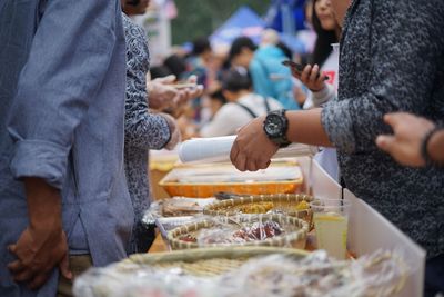 Midsection of people having food at market stall