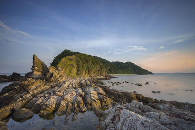 Scenic view of sea by mountain against sky