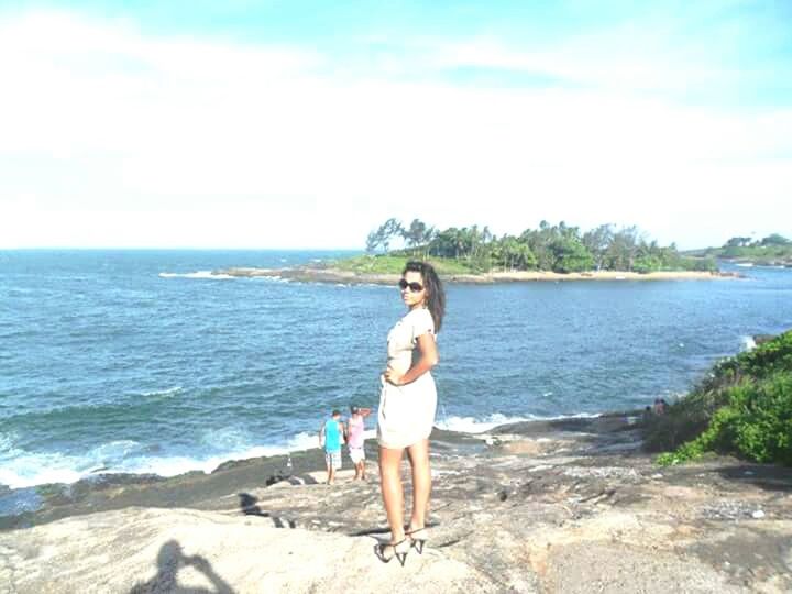 YOUNG WOMAN STANDING ON BEACH