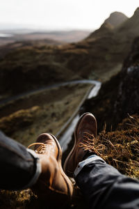 Low section of man relaxing on land against sky