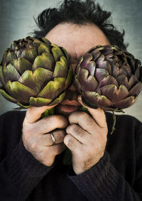 Close-up of mature man holding artichokes