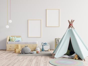 Tent with toys against blank picture frames at home