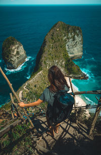 Rear view of woman standing on cliff by sea