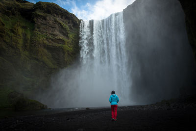 Traveler woman admiring skogafoss waterfall, in southern iceland