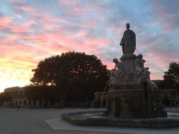 Statue in park against orange sky