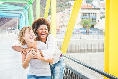 Happy lesbian couple embracing on bridge in city