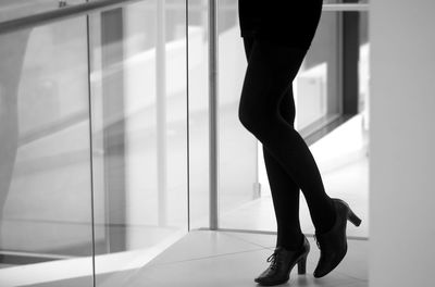 Low section of young woman wearing high heels standing on tiled floor