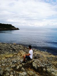 Young man sitting on rock at beach