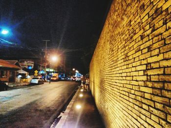 Illuminated street amidst buildings in city at night