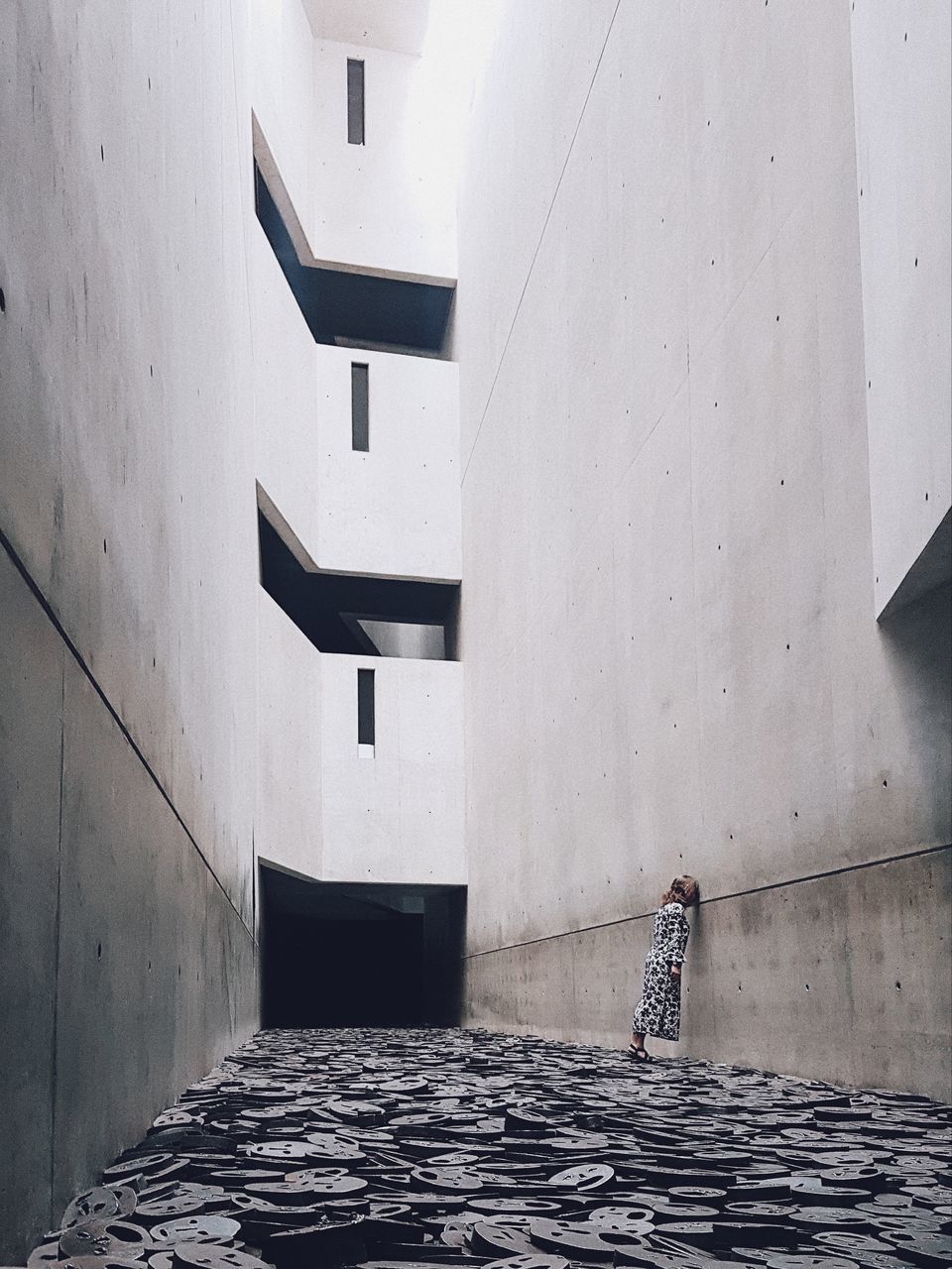 MAN WALKING ON FOOTPATH AGAINST BUILDING