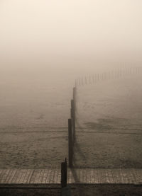 Wooden posts in sea against sky