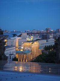 Illuminated buildings against blue sky at night