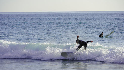 People in sea against sky