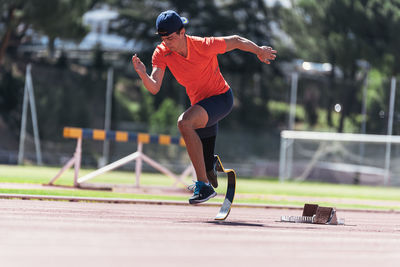 Man with prosthetic leg running on field