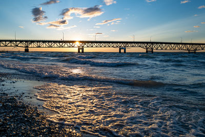 Bridge over sea against sky during sunset