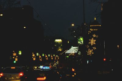 Cars on illuminated road in city at night