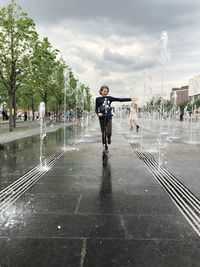 Full length of man standing on wet road in rainy season