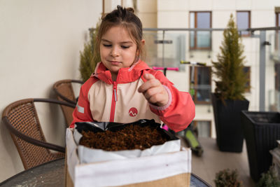 Portrait of young woman holding food on table