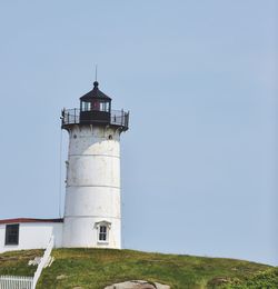 Low angle view of lighthouse by building against clear sky