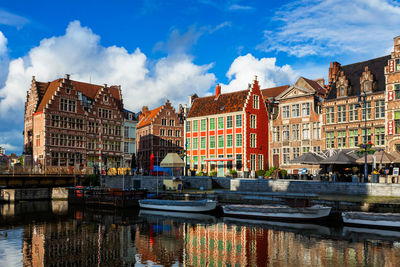 Canal by buildings in city against sky