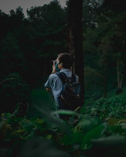 Full length of man photographing through camera in forest