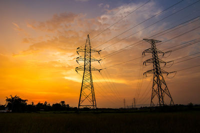 Silhouette electricity pylon on field against romantic sky at sunset