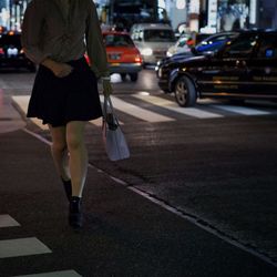 Low section of woman walking on street night