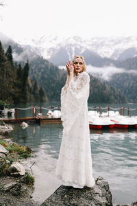 A tender sensual young woman bride in a fashionable wedding dress is standing in the rain in nature