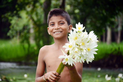 Portrait of smiling boy holding white water lilies