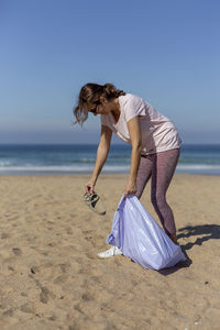 Woman with umbrella on beach against sea