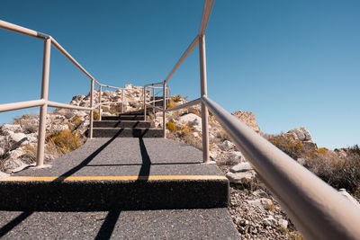 Low angle view of empty steps against clear blue sky at desert on sunny day