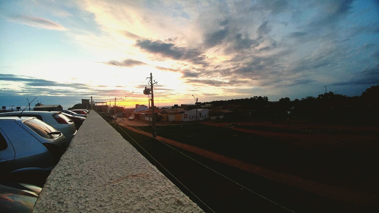 VEHICLES ON ROAD AGAINST SKY DURING SUNSET