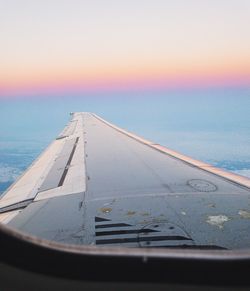 Close-up of airplane wing over sea against sky